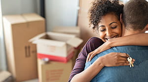 Couple hugging with house keys and packing boxes