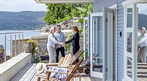 Two people shaking hands outside a home on the water