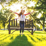Young woman in park jumps for joy