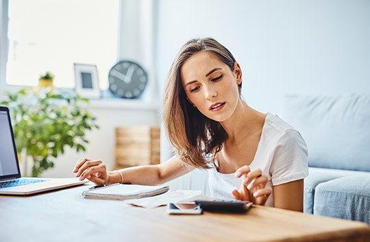 Person using calculator and laptop to compute finances
