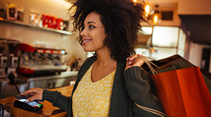 Black woman holding shopping bags paying for something using her phone