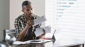 Person looking through paper mail at computer