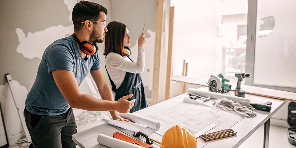 Couple looking at blueprints in room being remodeled