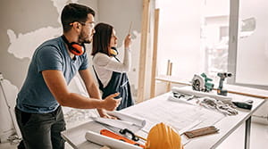 Couple looking at blueprints in room being remodeled 