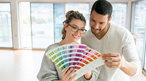 Man and woman in an empty white room looking at color swatches