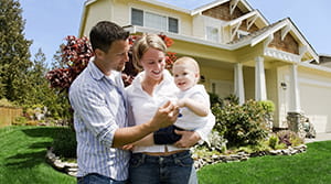 Father and mother holding a baby in the front yard of their new home financed by Banner Bank