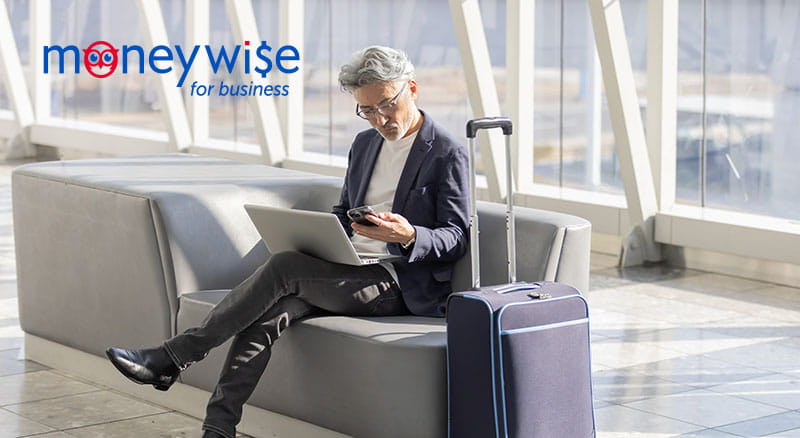 Person on laptop with suitcase and MoneyWise logo