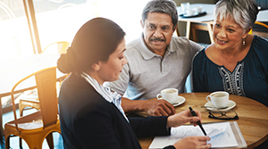 Middle age Hispanic couple sitting at a table with a female Hispanic banker