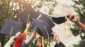 Group of college graduates raise caps in the air to celebrate