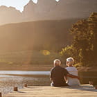 Retired couple sitting on dock at sunset