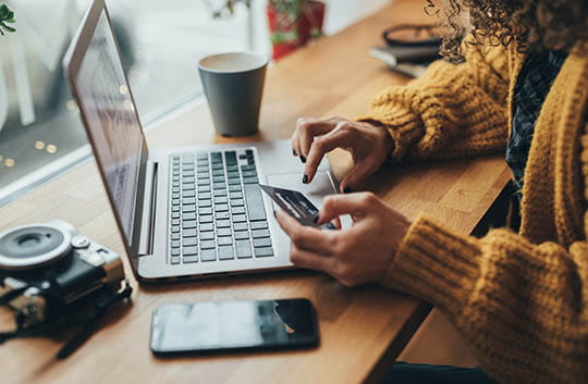 Person on laptop with card in hand