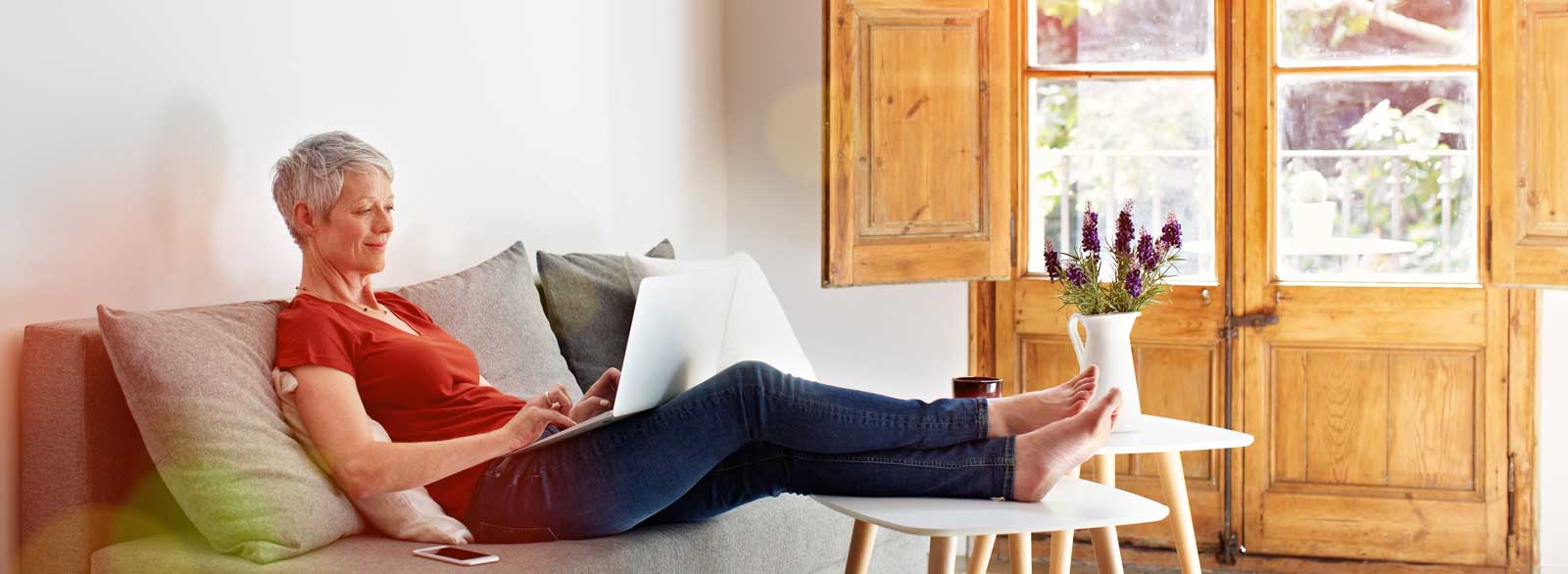 Woman uses laptop while relaxing on couch