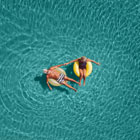 Older man and woman float in pool