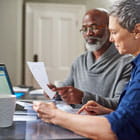 Older man and woman review financial statements to determine whether to open a Roth or Traditional IRA