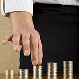 Male hand stacking coins in progressively taller columns 