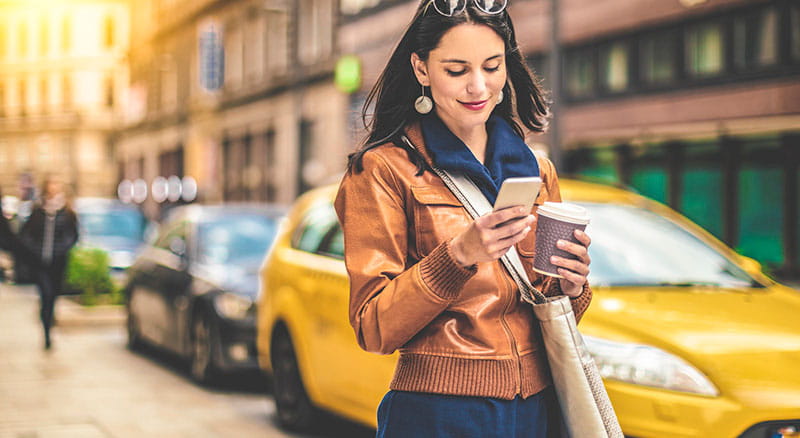 a woman checks her phone as she walks through the city