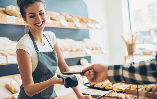 Woman in bakery accepts payment by mobile device