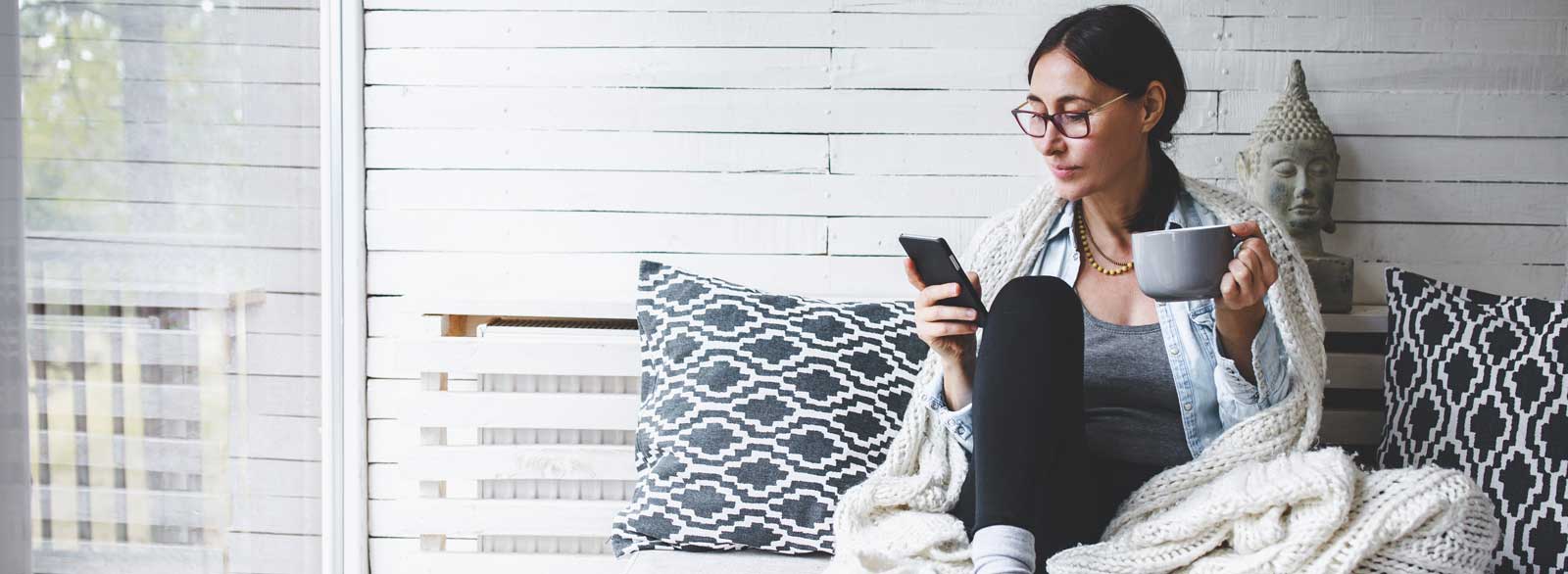 Woman sips coffee while banking on mobile phone