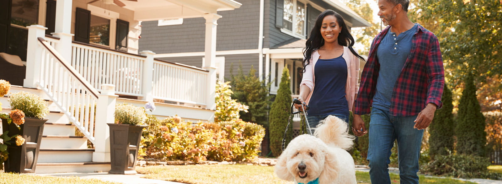 Couple walks dog through established neighborhood