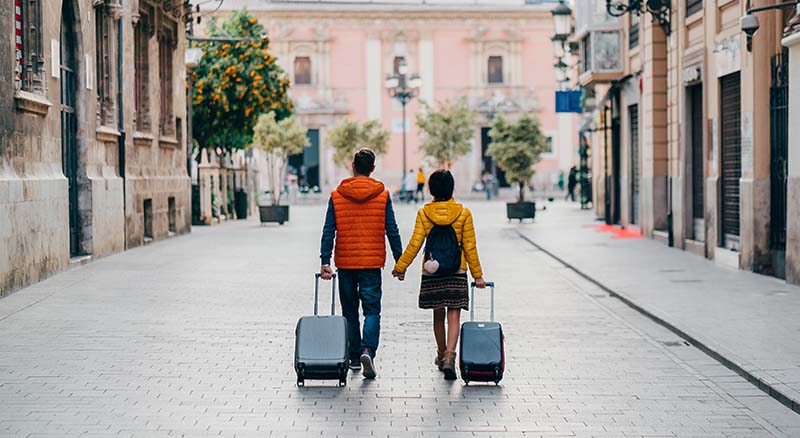 Couple walking with luggage in foreign country