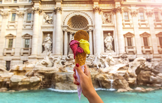 Hand holding gelato in front of Italian building