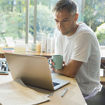 Person looking at calculator with mug in hand