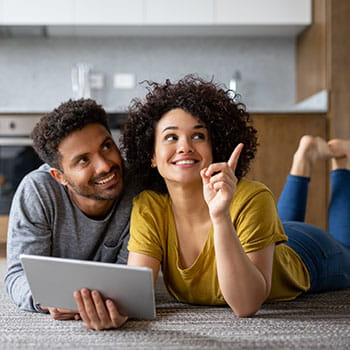 Photo of couple looking at a tablet and pointing in a home