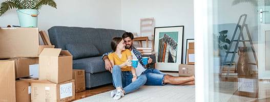 Two people sitting on the floor surrounded by boxes
