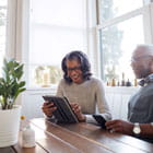 Older man and woman in the kitchen accessing Banner Online Banking using a tablet and mobile phone