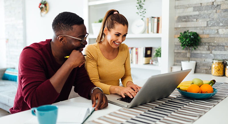 a diverse couple uses online banking in their kitchen