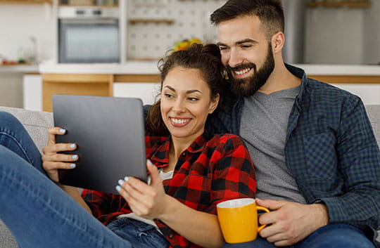 a couple relax on the couch and review their budget online