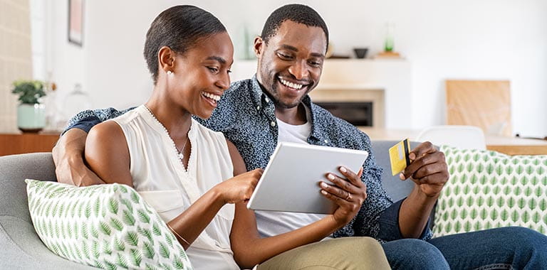 Two people looking at tablet with card in hand