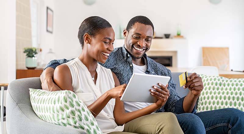 Two people looking at tablet with card in hand