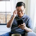 Person holding glasses up while looking at phone