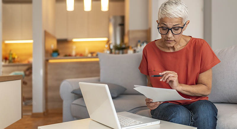 A woman checks her online banking on a laptop