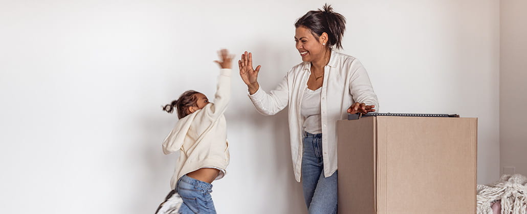 Mother and daughter high-fiving while packing a box