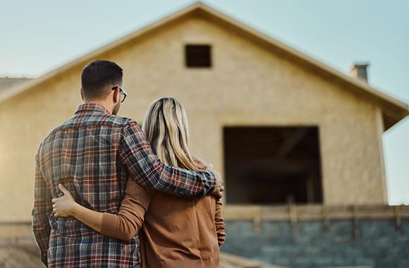 Two people looking at a home being built