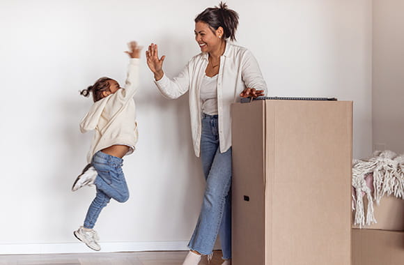 Mother and daughter high-fiving while packing a box