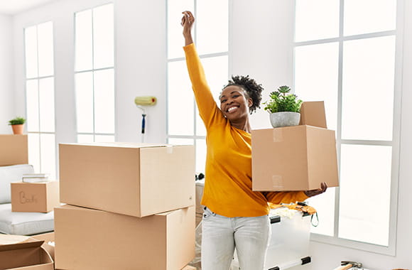 Person holding a moving box with arm in the air in new space