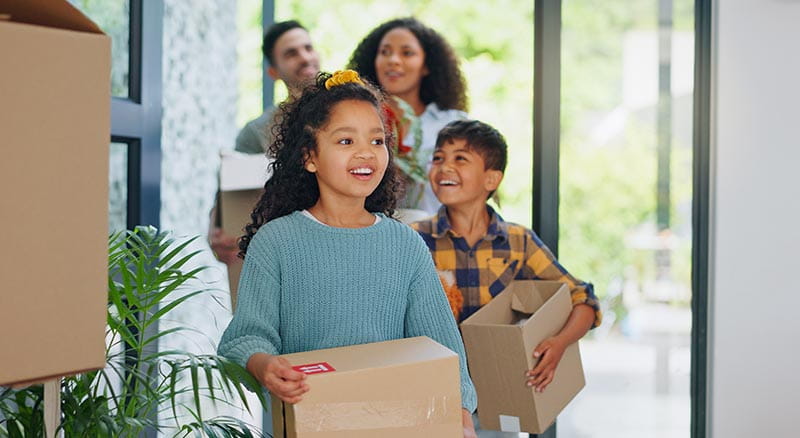 Family carrying boxes into new home