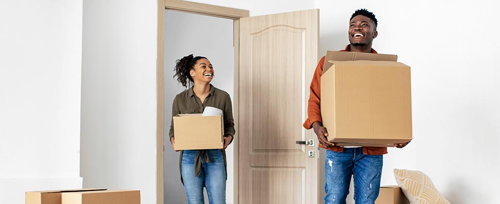 Two people carrying boxes into new home