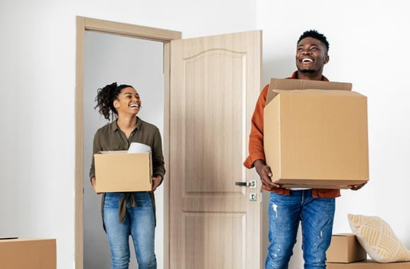 Two people carrying boxes into new home