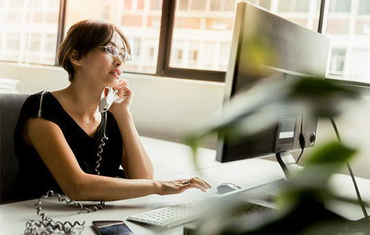 Woman working at computer while on the phone