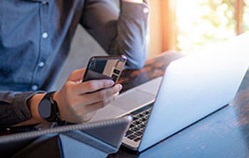 Person using laptop and cell phone