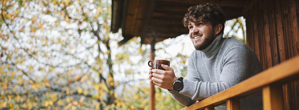 Person looking over porch with mug in hand