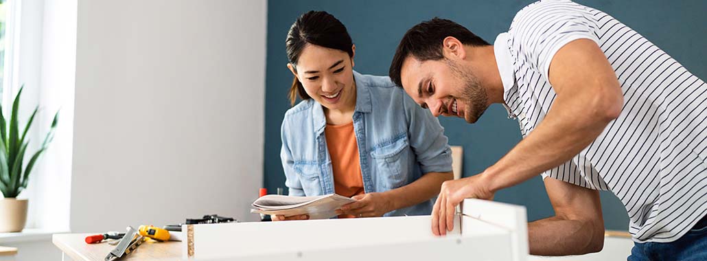 Two people putting together furniture