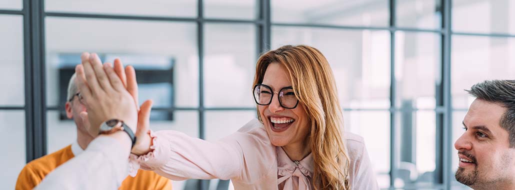 Two people high fiving in office