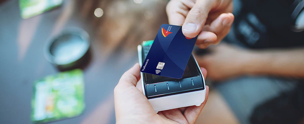 Person holding a Banner Bank credit card on a handheld card reader