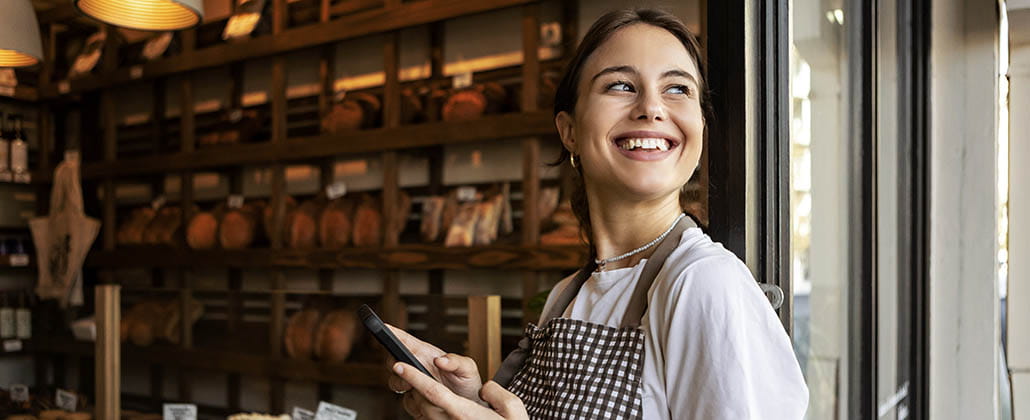 Person holding phone smiling in door of bakery