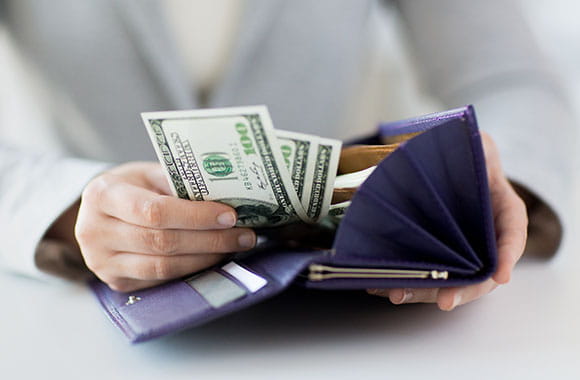 Person putting $100 bills in wallet